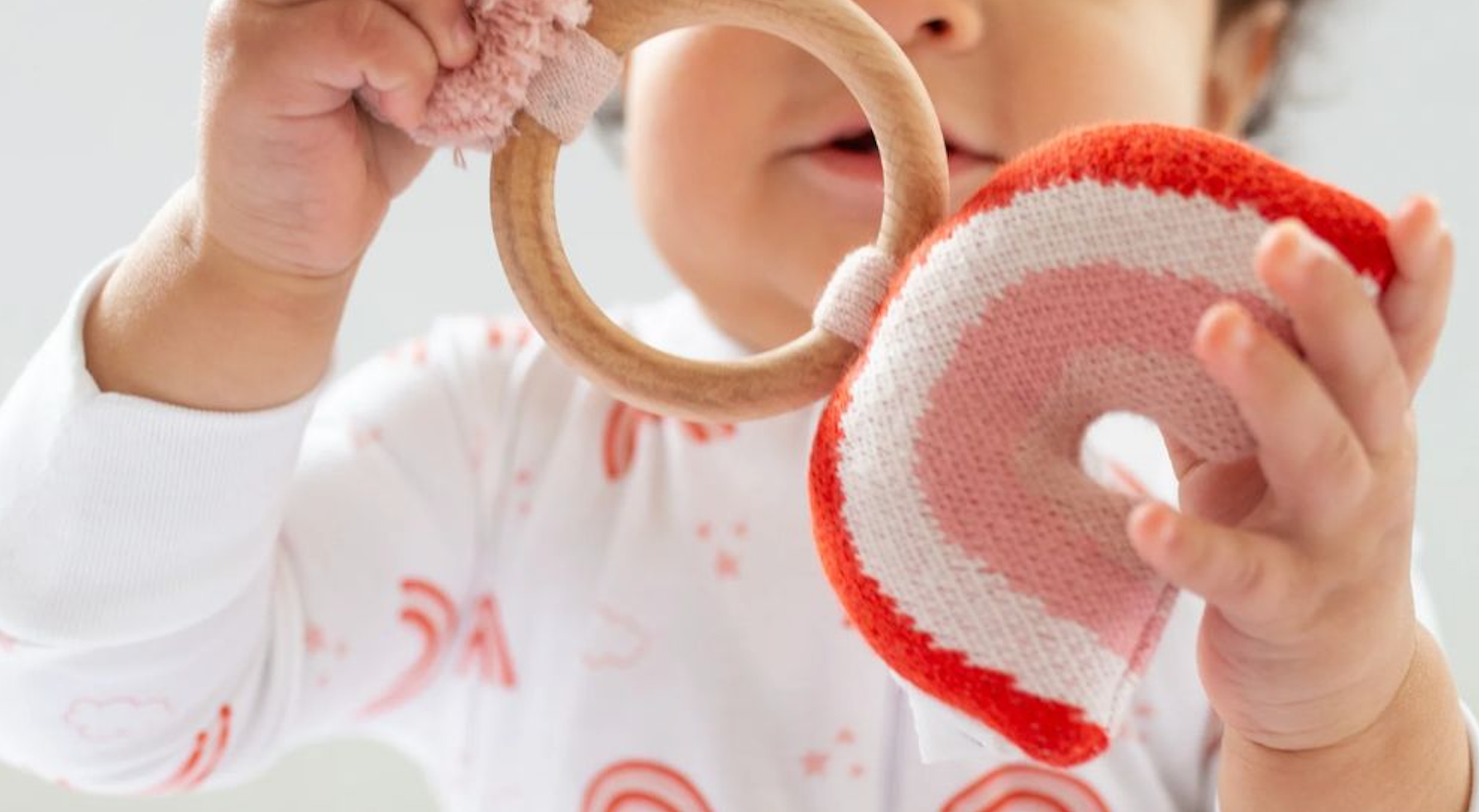 baby holding rainbow rattle