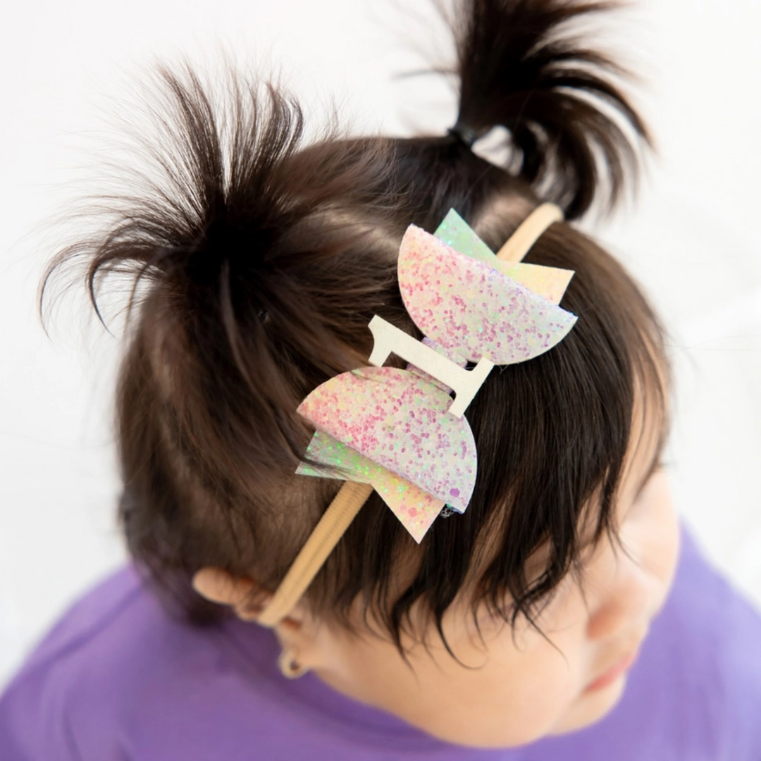 a baby wearing First Birthday Pastel Rainbow Baby Bow Headband 