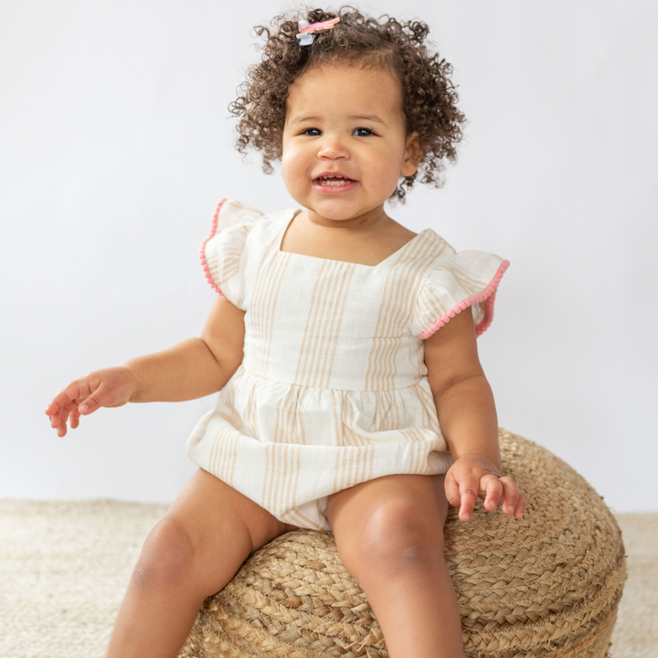 a baby girl wearing Bella Linen Bubble in Desert Mirage Stripe