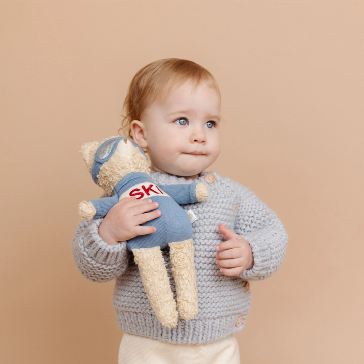 a baby holding the Benjamin Bear Ski Plushie