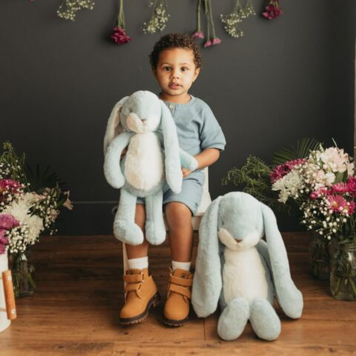 a little kid holding the Big Floppy Nibble Bunny in Maui Blue