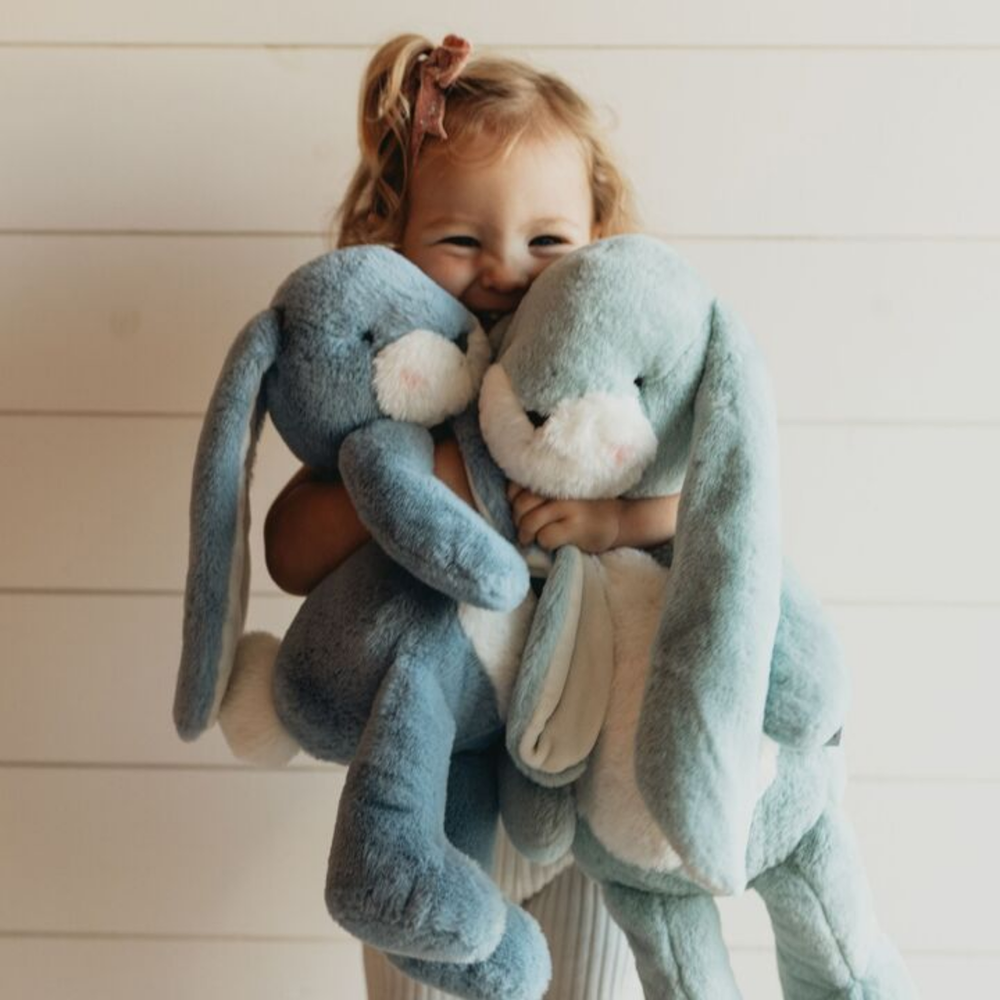 a little girl hugging the Big Nibble Bunny in Stormy Blue