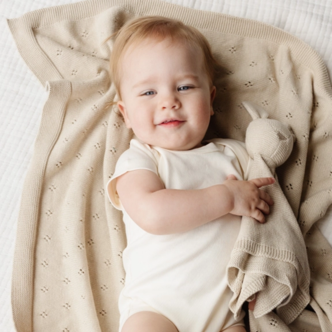 a baby holding the Bunny Lovey in Birch