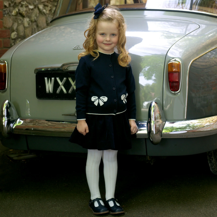 a little girl wearing Bow Intarsia Cardigan in Navy