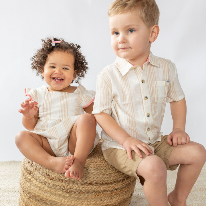 a baby girl and a little boy sitting at the wooden chair