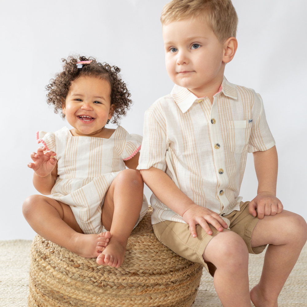 a baby girl and a boy sitting at the wooden chair