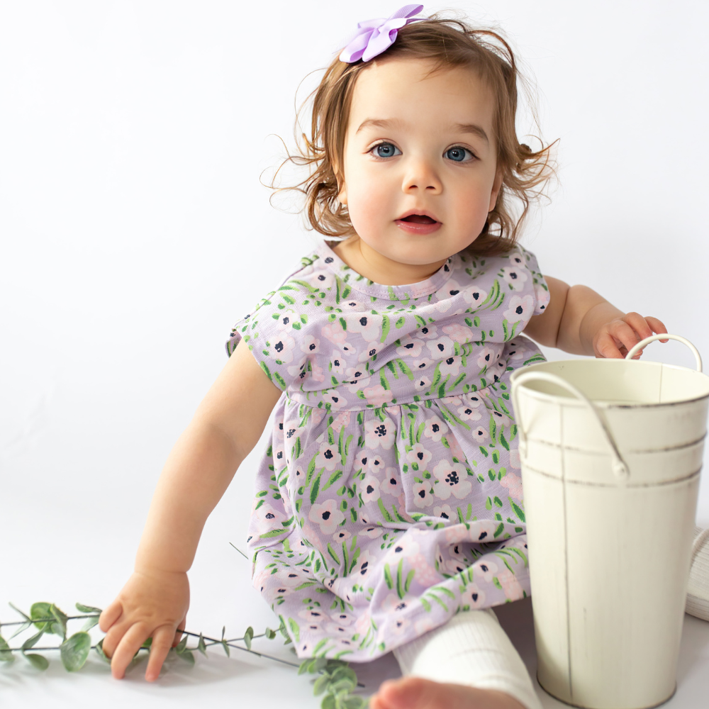 a baby girl wearing Carly Dress in Lavender Flowers