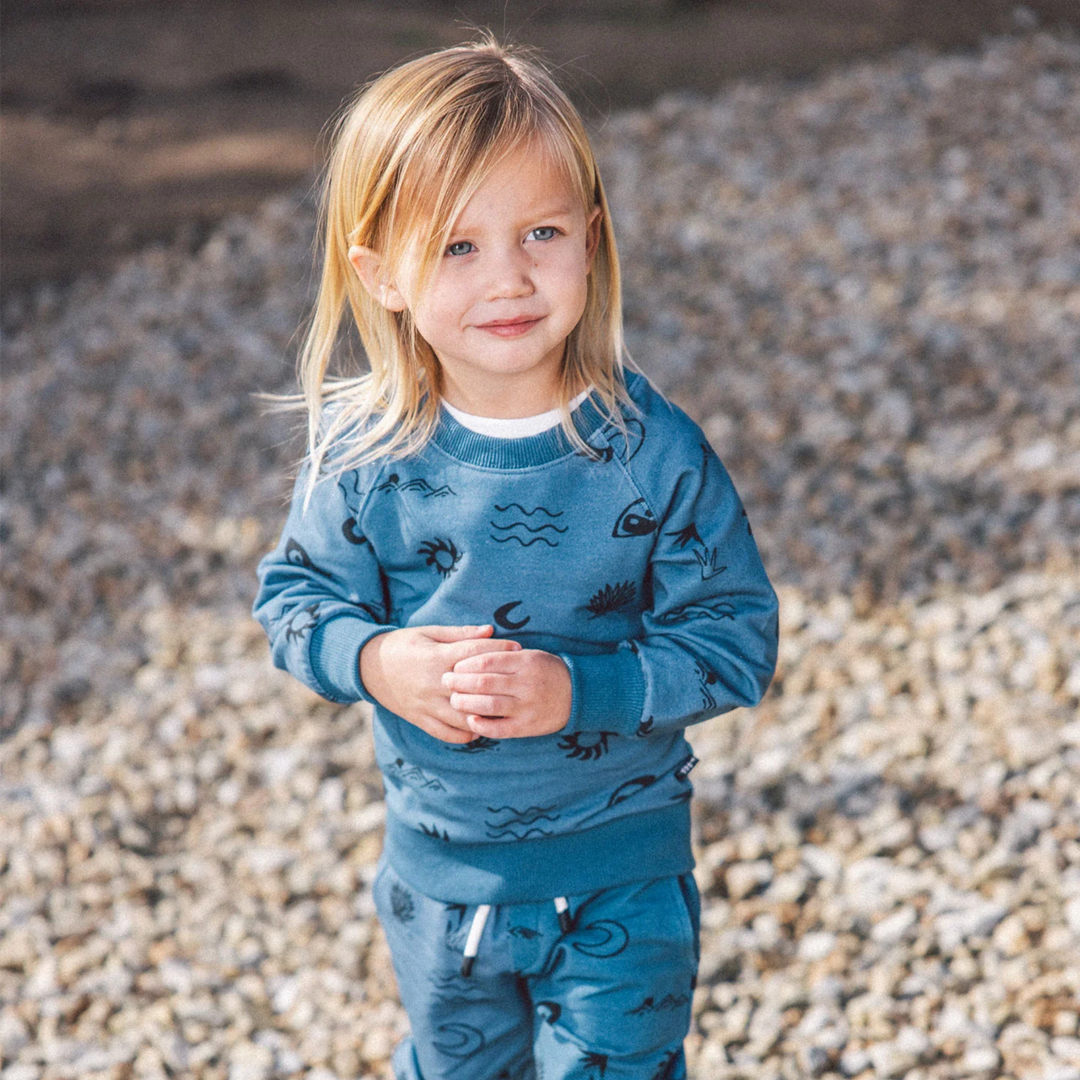 a little girl wearing Coast to Coast Baby Pullover in Slate Blue