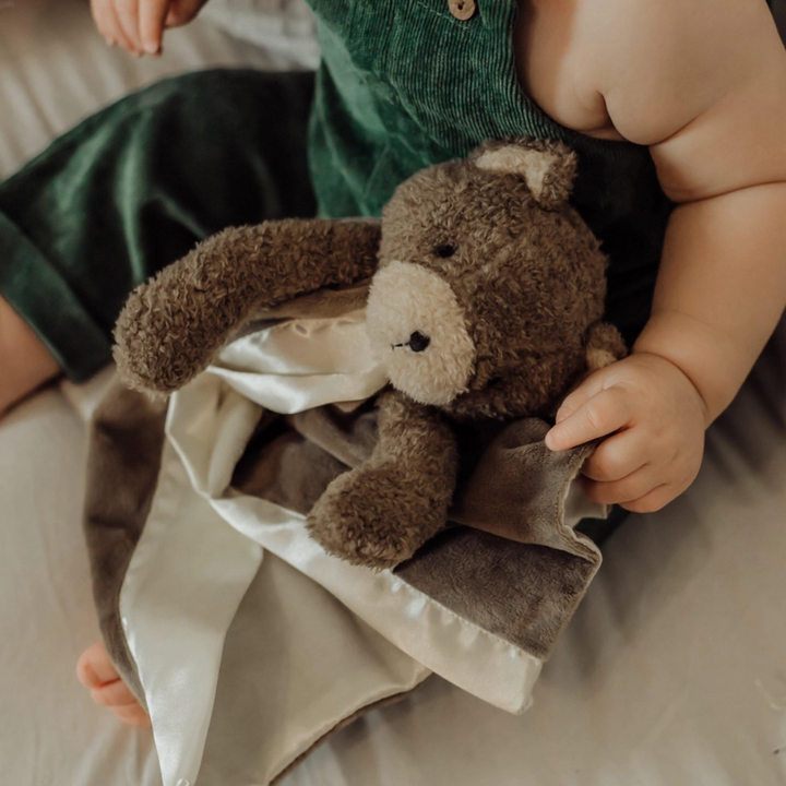 a baby holding Cubby Bear Buddy Blanket