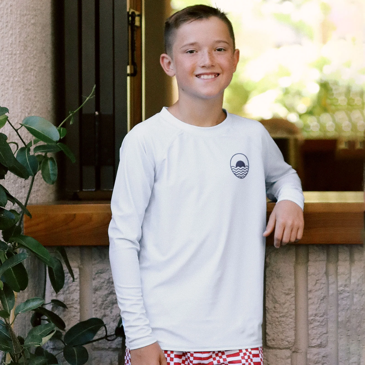 a boy wearing Icon Long Sleeve Rashguard in White