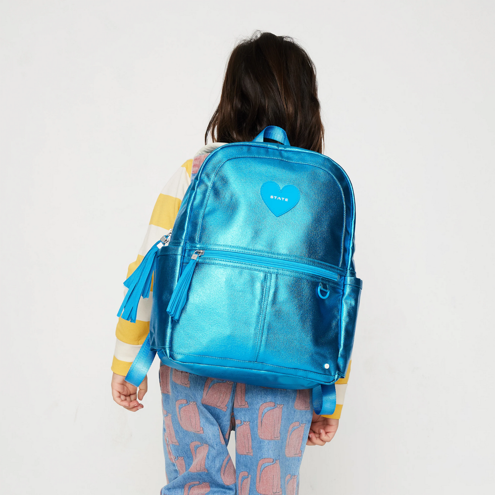 a little girl using Kane Kids Mini Travel Backpack in Metallic Blue