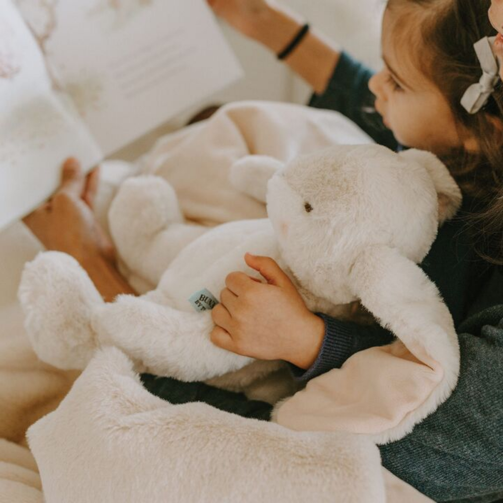 a girl holding the Little Nibble Bunny in Cream