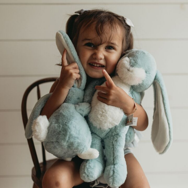 a girl hugging the Little Nibble Floppy Bunny in Stormy Blue