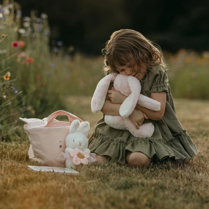 a little girl hugging the Little Nibble Bunny - Pink