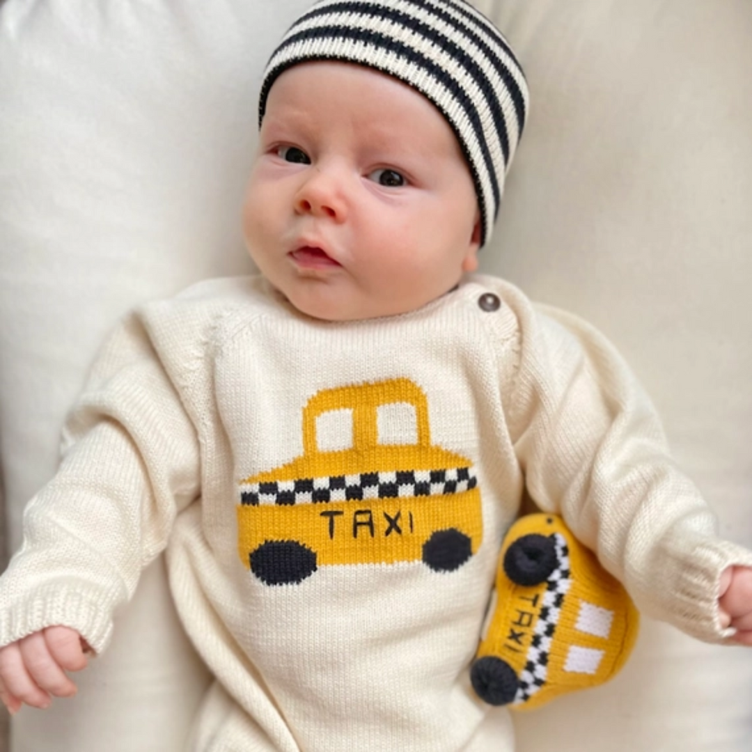 a baby lying beside Organic Taxi Rattle Toy