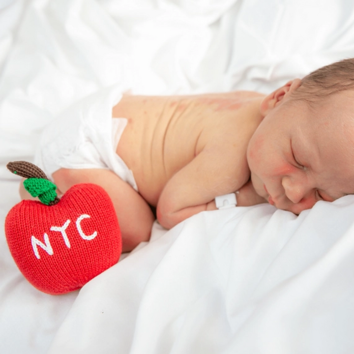 a baby sleeping beside Organic Big Apple Rattle Toy