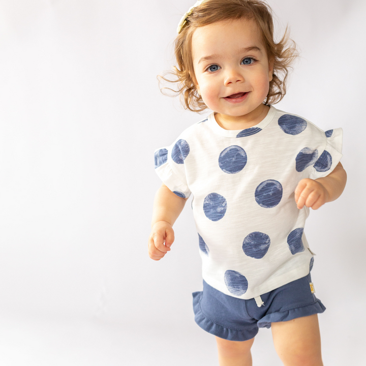 a baby girl wearing Rhea Ruffle Tee in Washed Indigo Dot