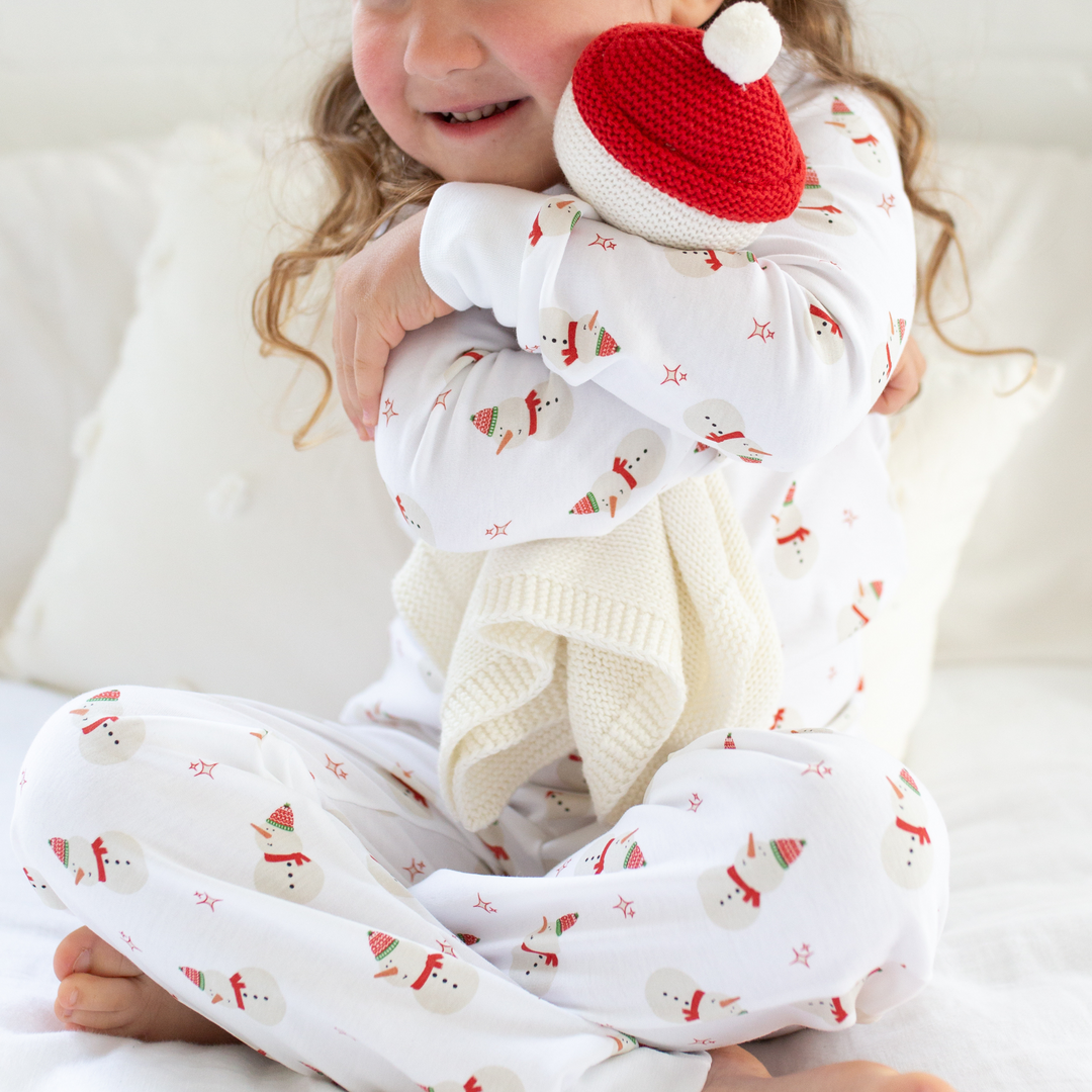 a little girl hugging Organic Snowman Lovey in White