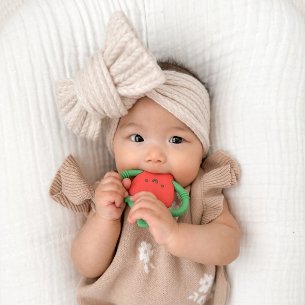 a baby biting the Strawberry Chew Crew