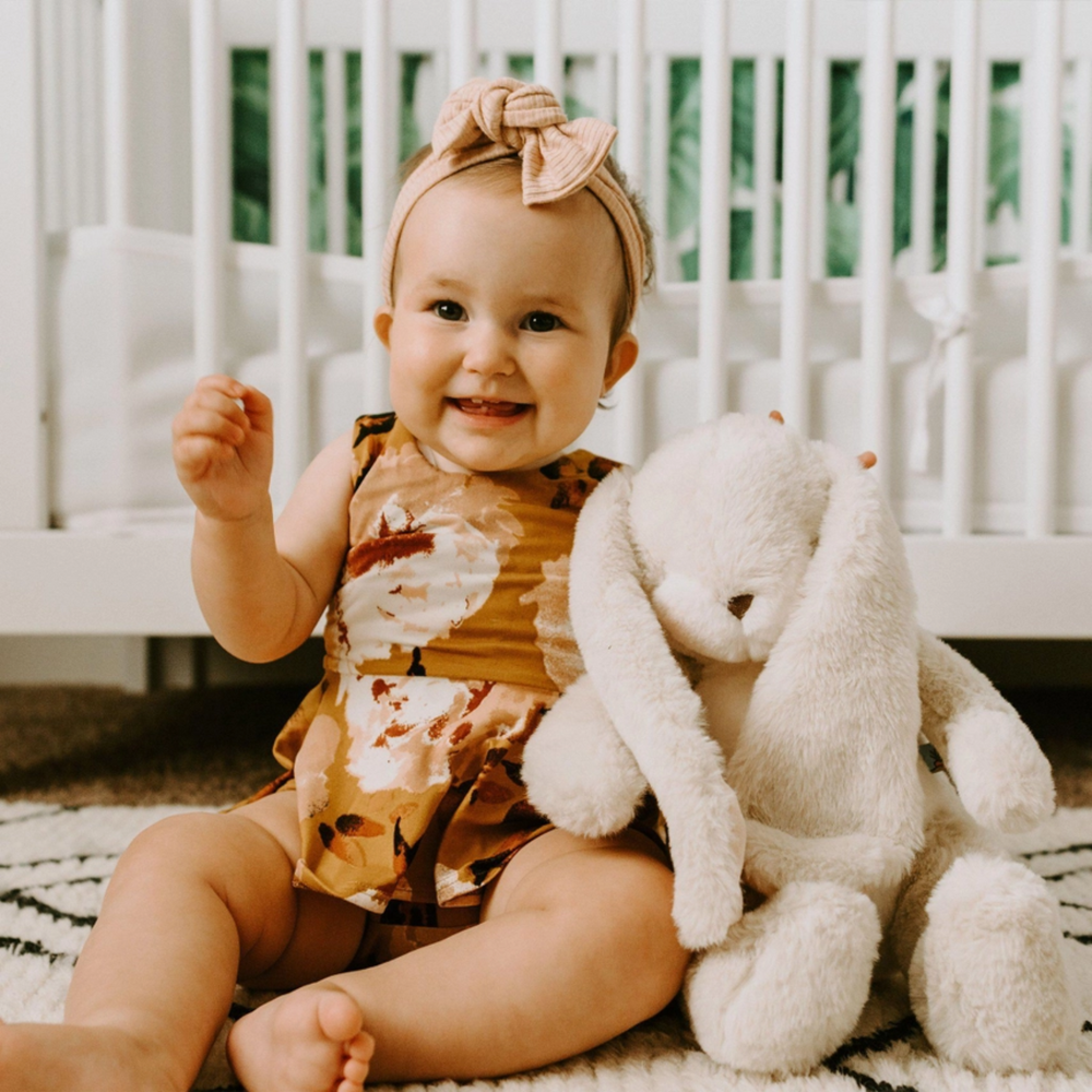 a baby girl sitting beside Sweet Nibble Bunny in Sugar Cookie