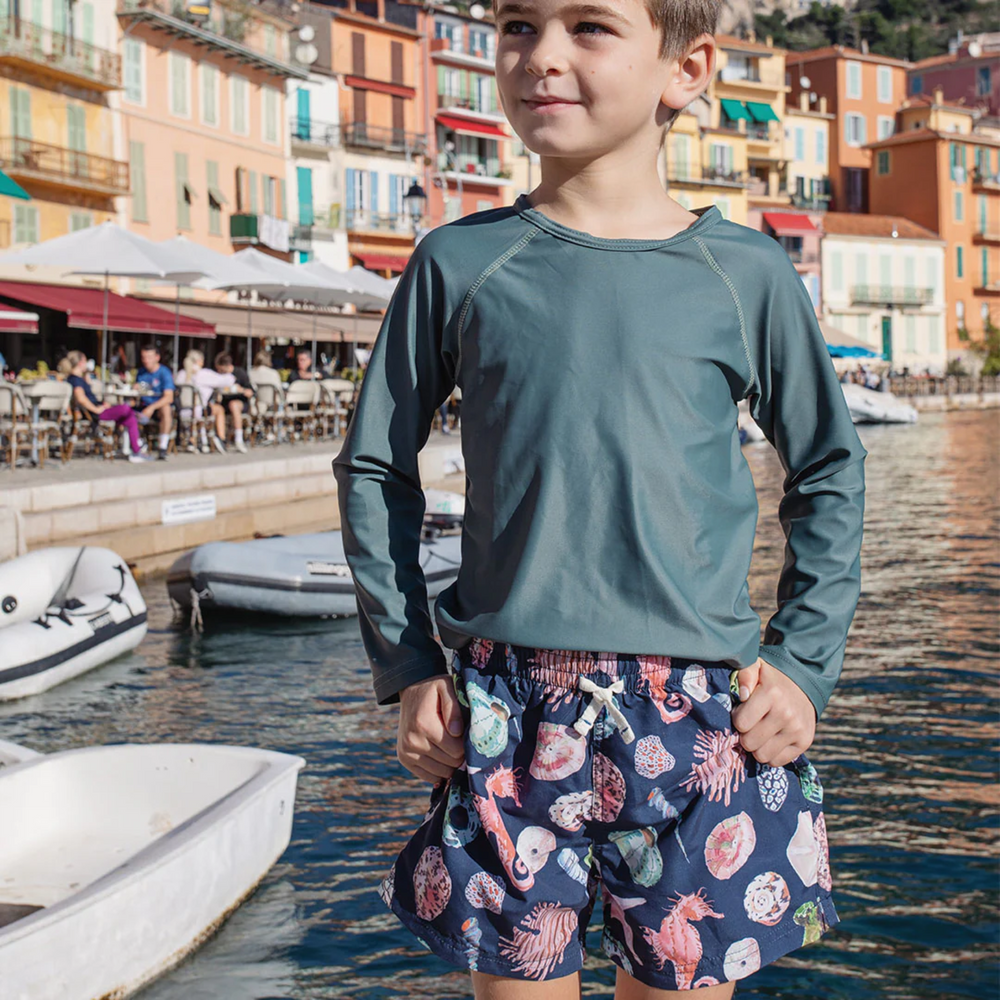 a boy wearing Swim Trunk - Navy Watercolor Shells