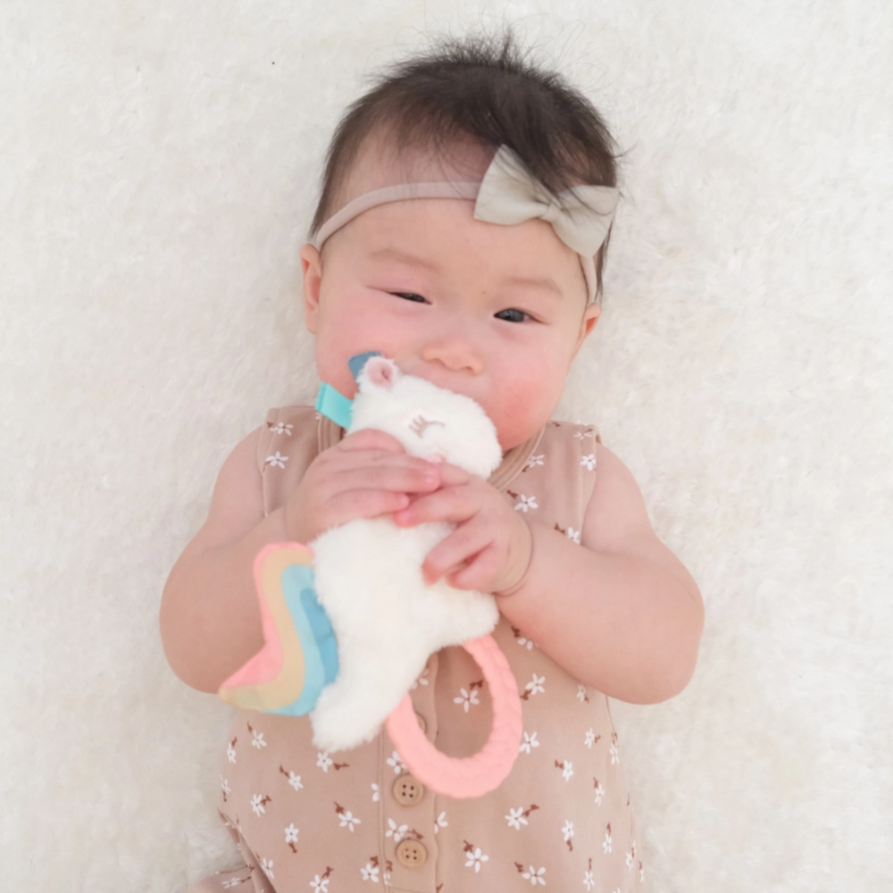 a baby playing Unicorn Pal Plush with Teether