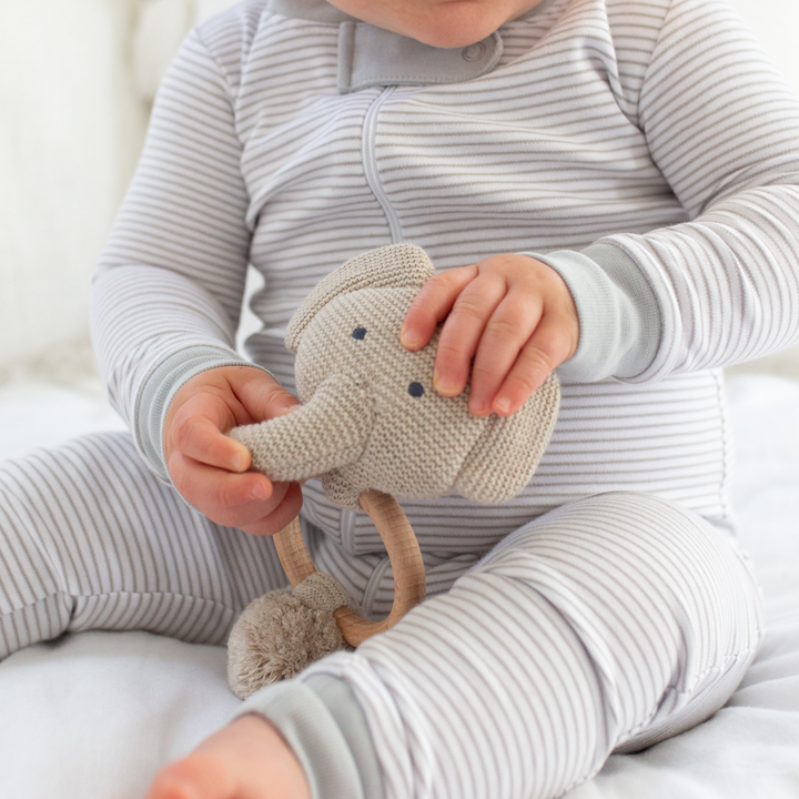 a baby holding the Organic Elephant Rattle in Oatmeal