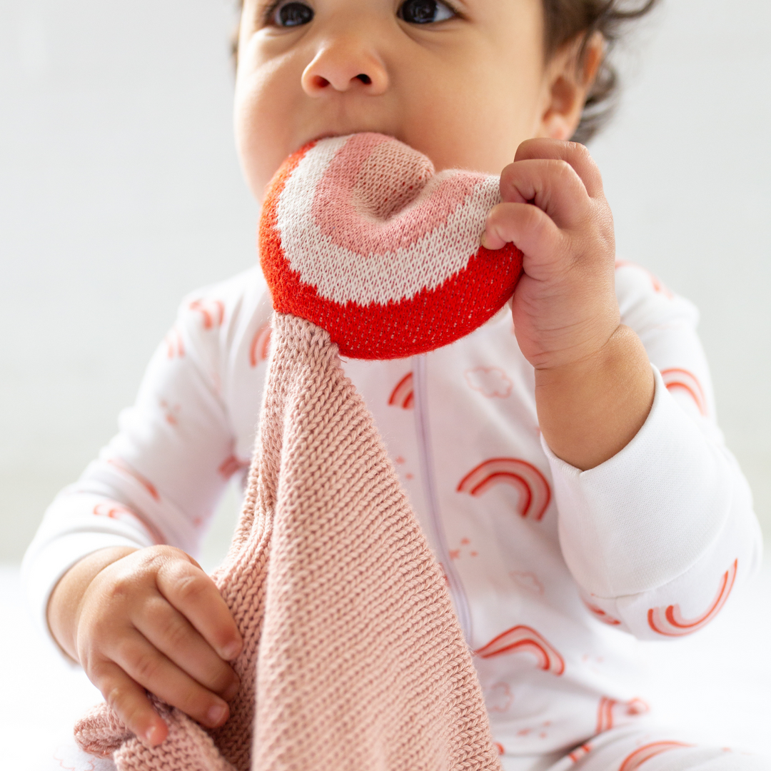 a baby holding Organic Rainbow Lovey in Pink Pearl