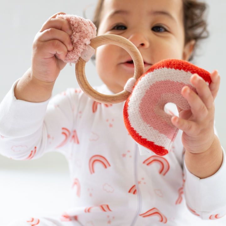 a baby holding Organic Rainbow Rattle in Pink Pearl