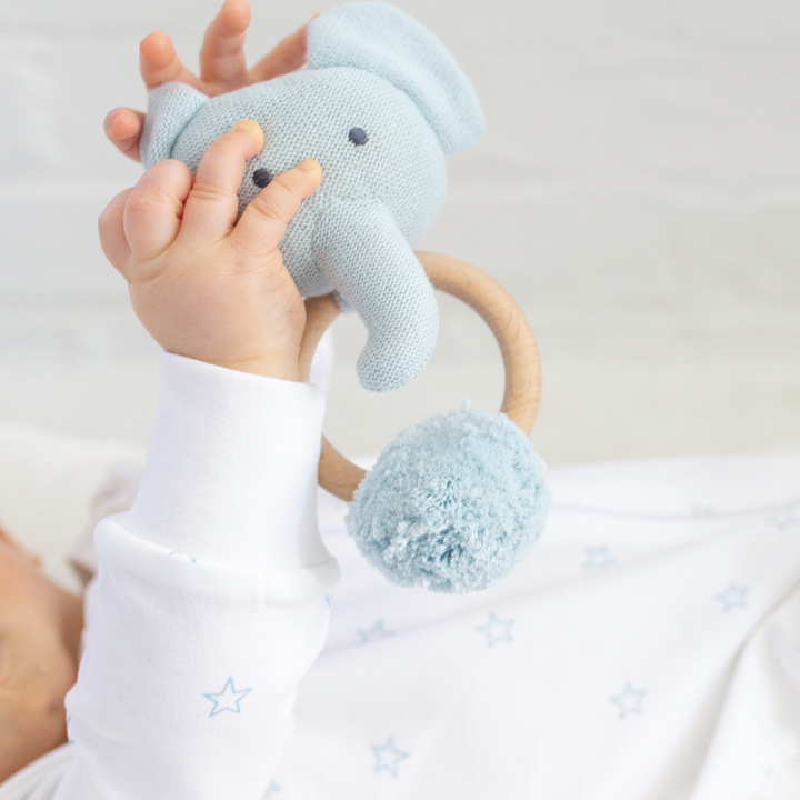 a baby holding Organic Knit Elephant Rattle in Blue