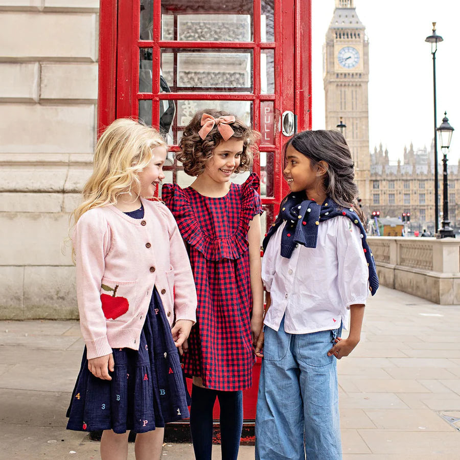 girls in front of phone booth wearing apple sweater and dresses