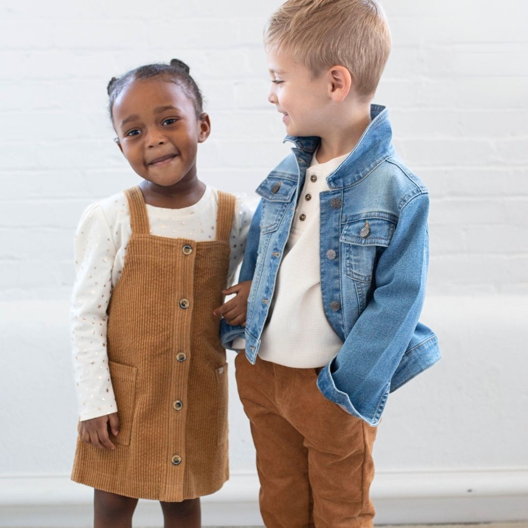 girl wearing brown jumper and boy wearing denim jacket brown pants 