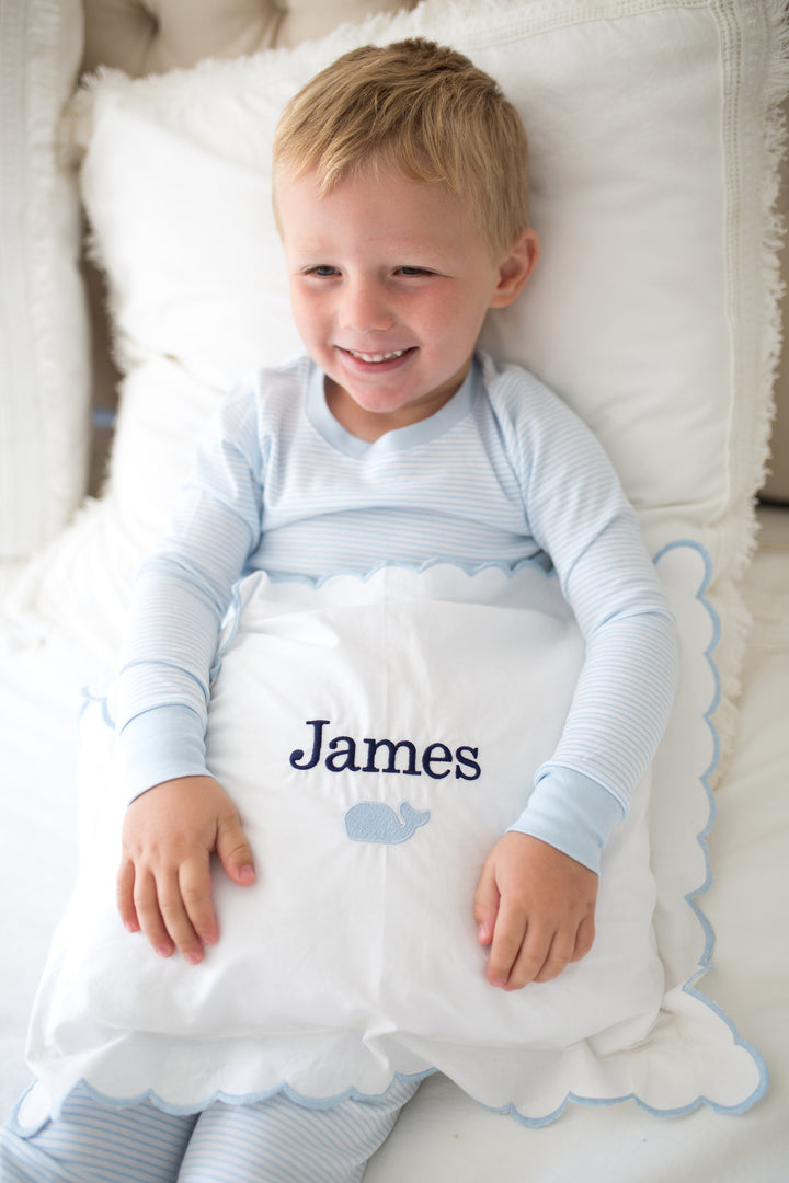 boy wearing striped pajamas with a monogram pillow