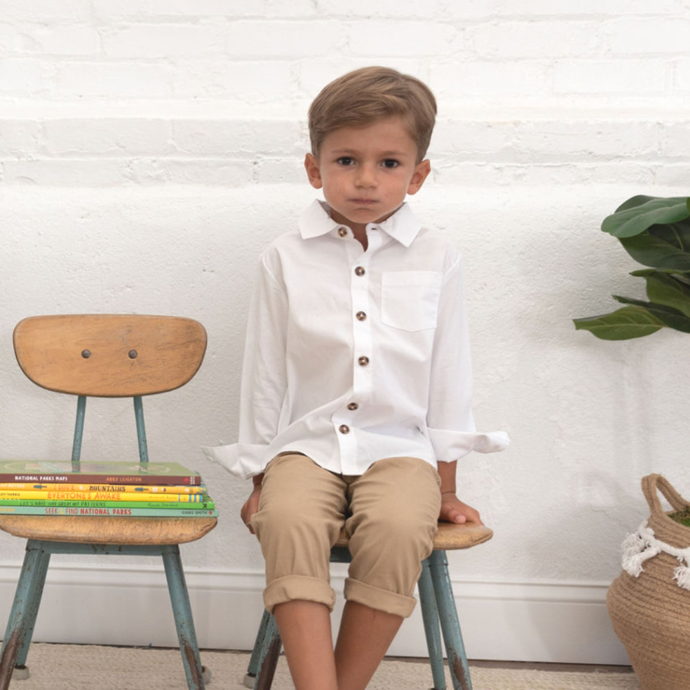 boy wearing white buttondown on chair