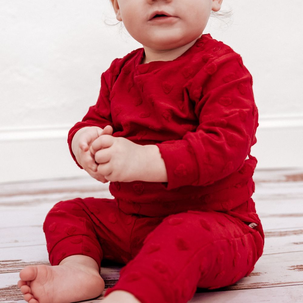baby wearing red sweatsuit with hearts