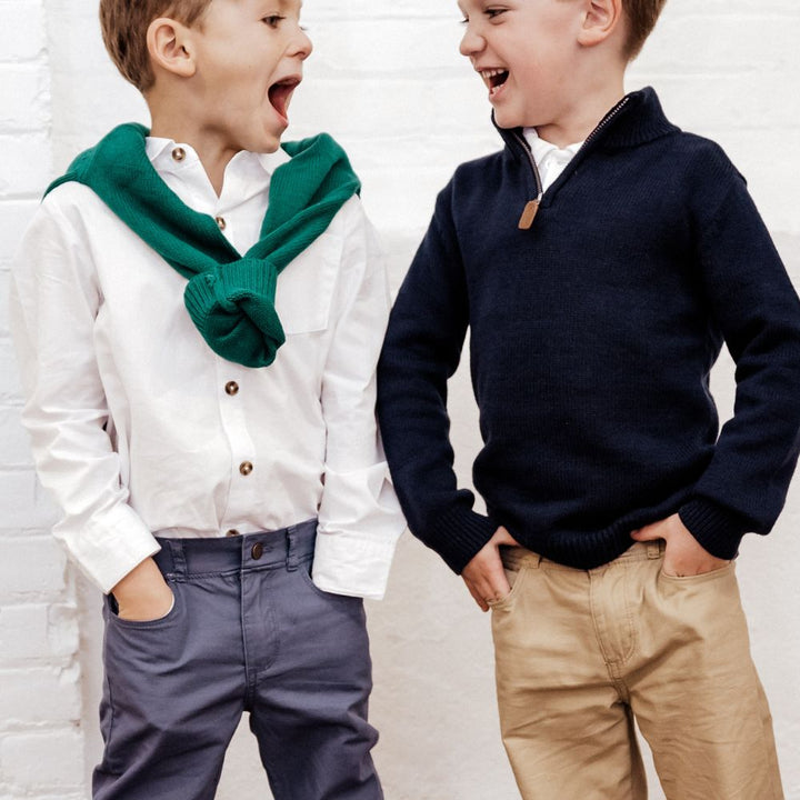 two boys wearing navy sweater and button down shirts with khakis
