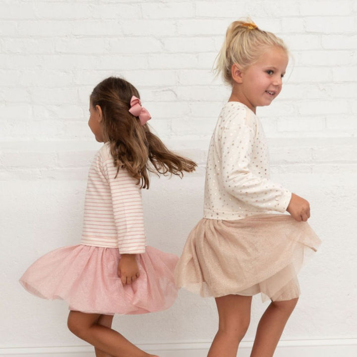two girls one wearing pink striped dress and ivory stars dress