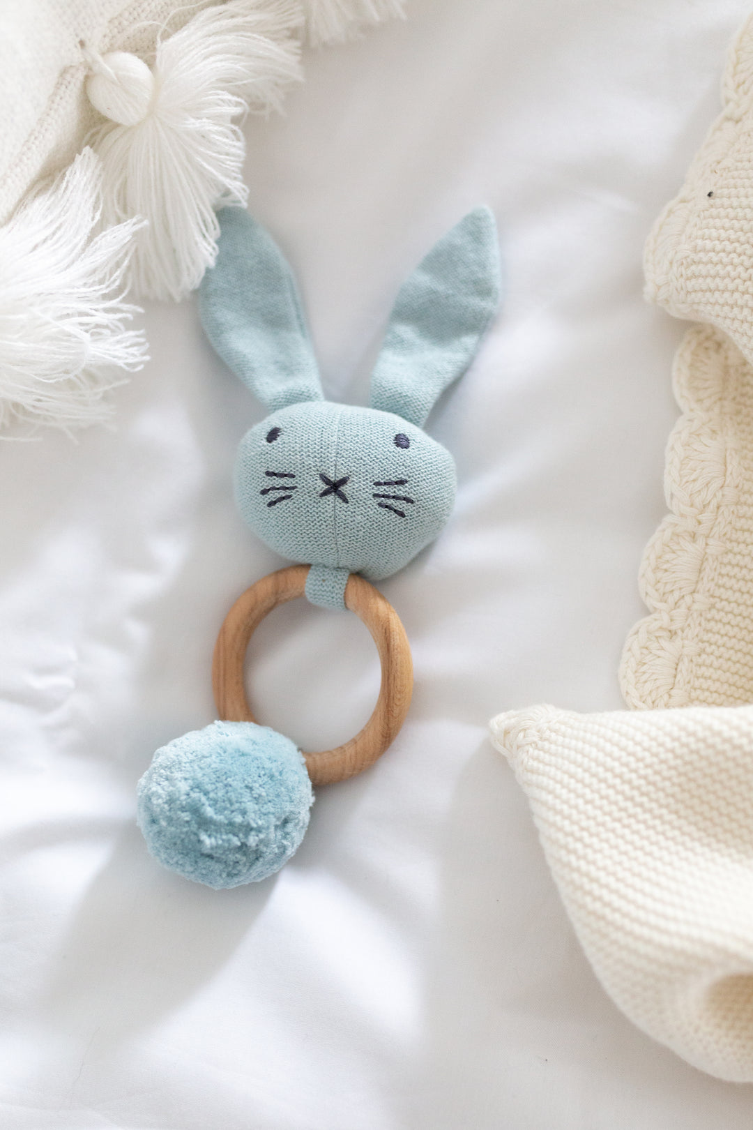 Organic Knit Bunny Rattle in Blue in a bed