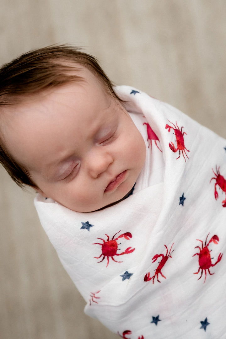 a baby wrap in a Organic Muslin Swaddle in Red Crab