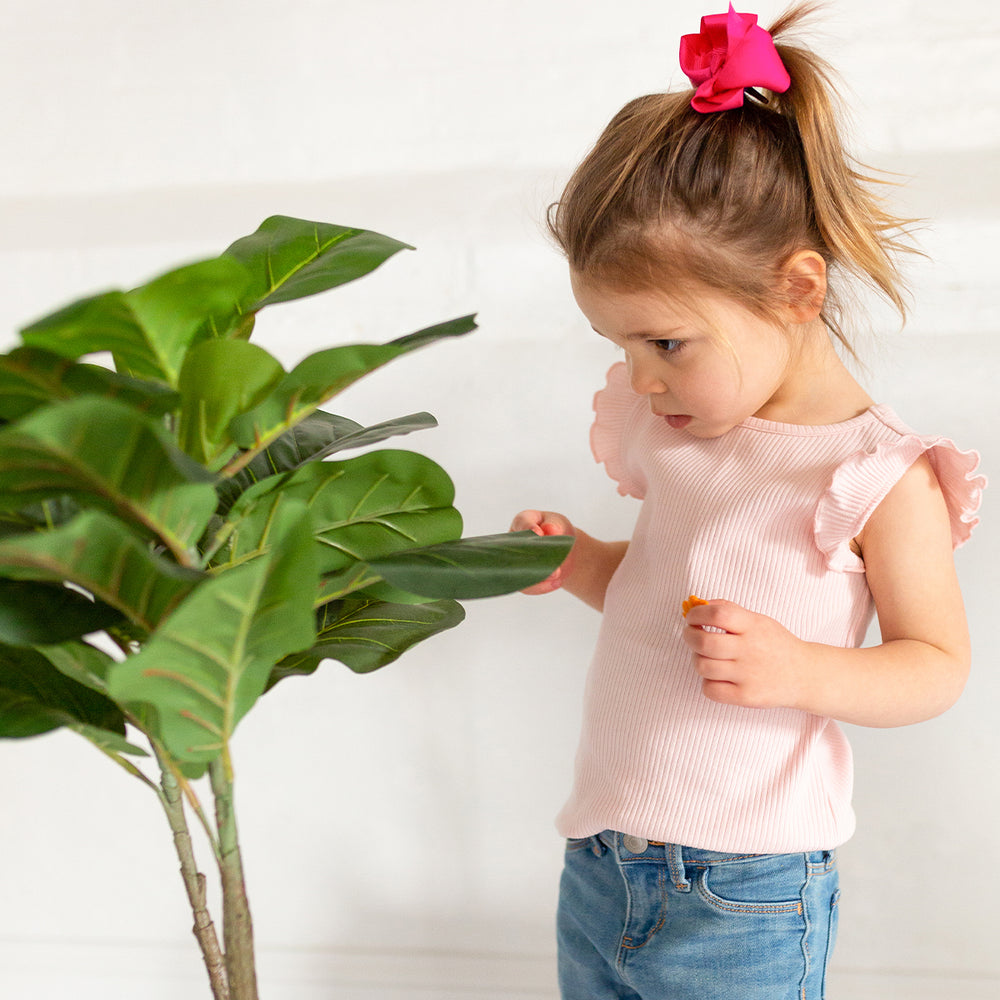 girl in pink tank top looking at plant