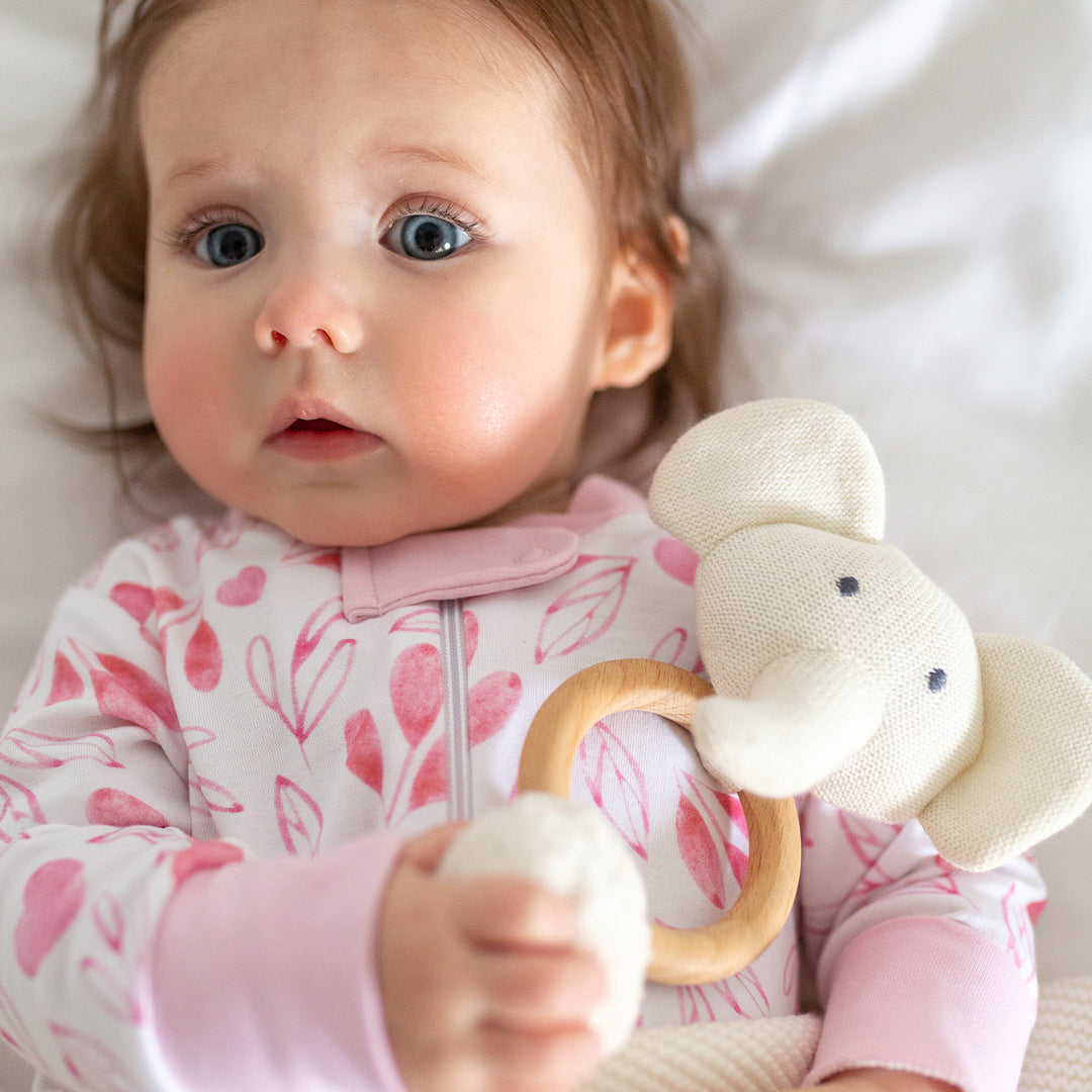 baby girl holding white elephant rattle